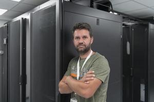 portret van mannetje technicus of netwerk beheerder staand dapper net zo een held met armen gekruiste in gegevens centrum server kamer. foto