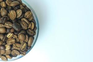 biologisch bruin geroosterd arabica koffie bonen in een glas kom Aan wit achtergrond. focus Aan koffie bonen in een schaal. beroemd en mooi zo kwaliteit. foto