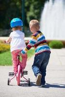 jongen en meisje in park aan het leren naar rijden een fiets foto