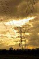 zon instelling achter de silhouet van elektriciteit pylonen - levendig kleur effect foto