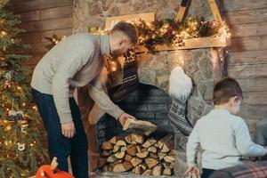 vader en weinig zoon stack hout in een haard foto