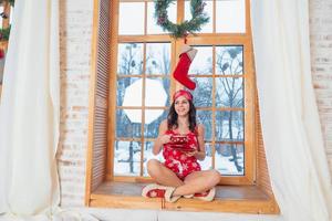 mooi jong brunette vrouw vervelend rood pyjama zittend huis door de venster foto