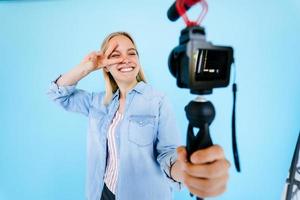 mooi meisje blogger verlicht zelf Bij camera geïsoleerd blauw achtergrond foto