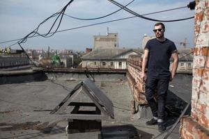 de man in de authentieke zelfkant van laarzen en jeans op het dak van het gebouw in de oude stad foto