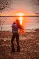 vrouw genieten van tijd ontspannende door de mooi meer Bij zonsopkomst. foto