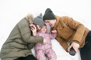 pa, mam en weinig dochter zijn aan het liegen Aan de sneeuw foto