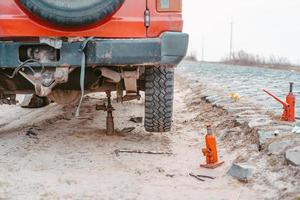 een Mens verhoogt Aan een jack 4x4 uit weg vrachtauto foto