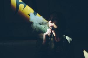 meisje zit en rookt elektronisch sigaret foto