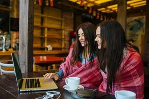 twee meisjes kijken naar iets in de laptop foto