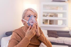 ziek ouderen vrouw maken inademing, geneeskunde is de het beste geneesmiddel. ziek senior vrouw vervelend een zuurstof masker en ondergaan behandeling. senior vrouw met een inhalator foto