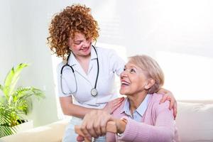 dichtbij positief verhouding tussen senior geduldig en verzorger. gelukkig senior vrouw pratend naar een vriendelijk verzorger. jong mooi verzorger en ouder gelukkig vrouw foto