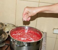 een vrouw bereidt zich voor vers gezond sap van tomaten. vers gemaakt tomaat sap is gekookt in een pan en bewaard gebleven voor langetermijn opslag. eetpatroon concept voor een gezond levensstijl. foto