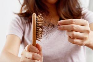 achterzijde visie jong vrouw bezorgd over haar- verlies probleem, hormonaal disbalans, spanning concept. veel haar- vallen na kammen in haar- borstel in hand. vrouw ontward haar haar- met een kam, Gezondheid zorg foto