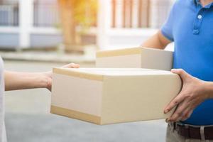 pakket levering Mens slijtage beschermend handschoenen blauw en masker, beschermen hygiëne kiem en bacterie van een pakket door een onderhoud sturen naar huis. hand- Holding verzenden en inzending klant accepteren een van doos foto