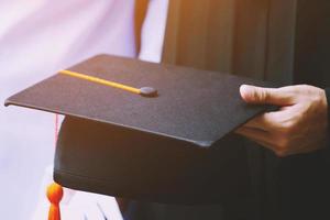 leerling houden hoed in hand- gedurende aanvang succes afgestudeerden van de universiteit, concept onderwijs felicitatie. diploma uitreiking ceremonie. zacht focus foto