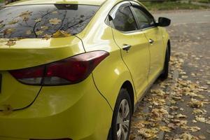 geel auto. taxi in herfst. de auto is in de parkeren kavel. foto