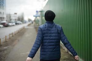 de vent wandelingen langs de schutting. een Mens in een zwart hoed. foto