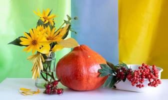 herfst achtergrond voor dankzegging. oranje pompoen en geel bloemen Aan een wit houten tafel foto