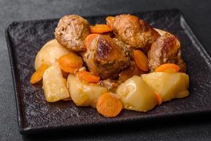 rundvlees vlees en groenten stoofpot Aan een zwart bord met geroosterd aardappelen foto