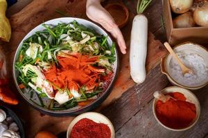Koreaans Dames voorbereidingen treffen naar maken kimchi, draag- een kop van vers groenten bestaande van radijs, Chinese kool, wortels, appels, uien, knoflook. gefermenteerd Koken. foto