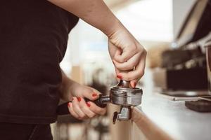barista persen grond koffie gebruik makend van knoeien. detailopname visie Aan handen foto