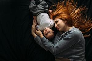 gelukkig moeder met baby aan het liegen samen Aan bed foto