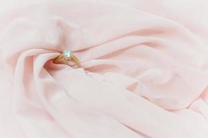 bruiloft ring Aan roze kleding stof voor Valentijn dag of bruiloft achtergrond foto