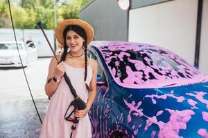 vrouw met slang staat door auto gedekt in roze schuim foto