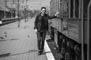 een Mens gekleed in jeans Aan de achtergrond van de trein en de station foto