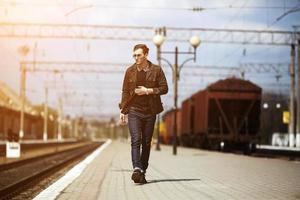 een Mens gekleed in jeans Aan de achtergrond van de trein en de station foto