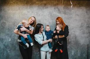 drie moeders met hun kinderen poseren Aan camera foto
