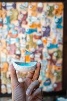 man's hand- houdt een speelgoed- zeilboot met een blauw vlag foto