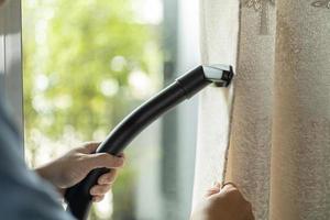 Mens droog schoonmaak gordijn met vacuüm schoner. in leven kamer Bij huis. foto