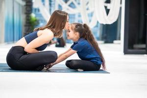 jong volwassen moeder en weinig dochter samen beoefenen yoga foto