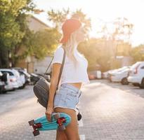 jong meisje met een skateboard Aan een auto park. foto