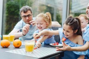 gelukkig familie aan het eten vers fruit ontbijt foto