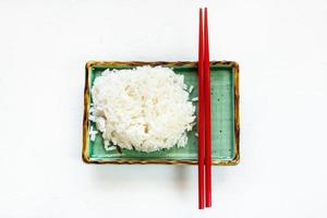 gekookt rijst- en rood eetstokjes Aan bord Aan wit foto