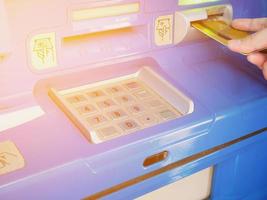vrouwelijke hand die ATM-kaart in de ATM-bankmachine steekt foto