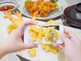 nemen foto van garnaal tempura Aan wit bord met smartphone
