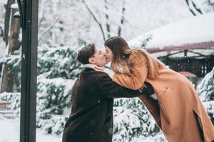 jong vent en mooi meisje kus in een besneeuwd park foto