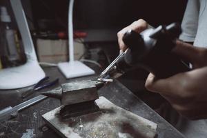 in de werkplaats, een vrouw juwelier is bezig solderen sieraden foto