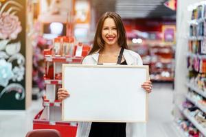 glimlachen brunette vrouw Holding wit blanco bord foto