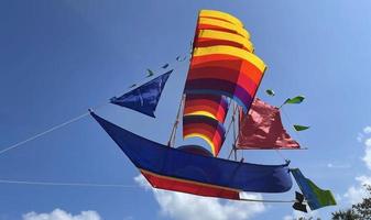 vliegend schip, regenboog gekleurde schip vlieger vliegt Aan de blauw lucht en wolk foto