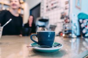 kop van zwart koffie, lepel, houten tafel, Bij een cafe foto