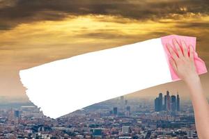 hand- verwijdert smog lucht over- stad door roze vod foto
