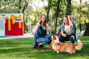 twee vrouw vriend in de park Speel met weinig hond foto