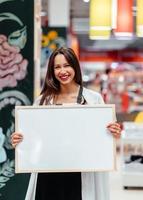 glimlachen brunette vrouw Holding wit blanco bord foto
