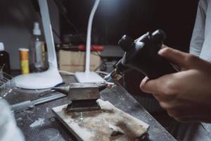 in de werkplaats, een vrouw juwelier is bezig solderen sieraden foto