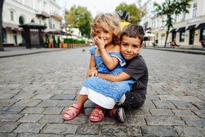 weinig jongen en meisje zijn zittend Aan de straat foto