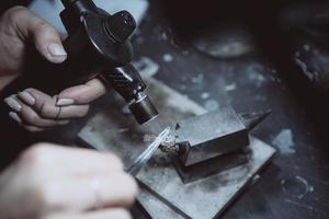 in de werkplaats, een vrouw juwelier is bezig solderen sieraden foto